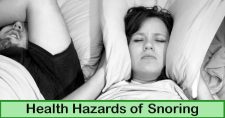 Health Hazards of Snoring. Picture of a caucasian male and female laying in bed, he is sleeping and she is holding a pillow around her ears to block out his snoring.